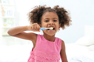 Primary school girl brushing her teeth