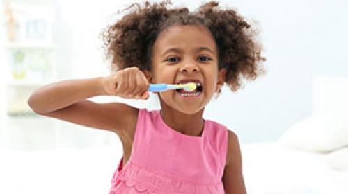 Primary school girl brushing her teeth